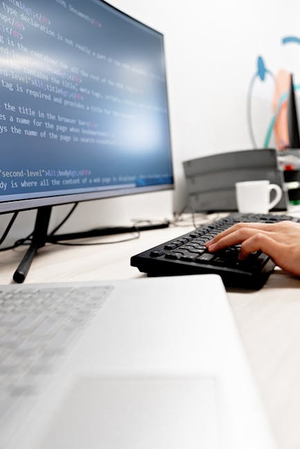 A person using a computer mouse in a gardening context, with a background showing a screen displaying code, a white cup, and colorful sketches of plants on the wall. The workspace includes a white des