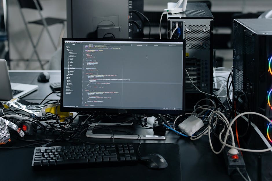 A person using a computer mouse in a gardening context, with a background showing a screen displaying code, a white cup, and colorful sketches of plants on the wall. The workspace includes a white des